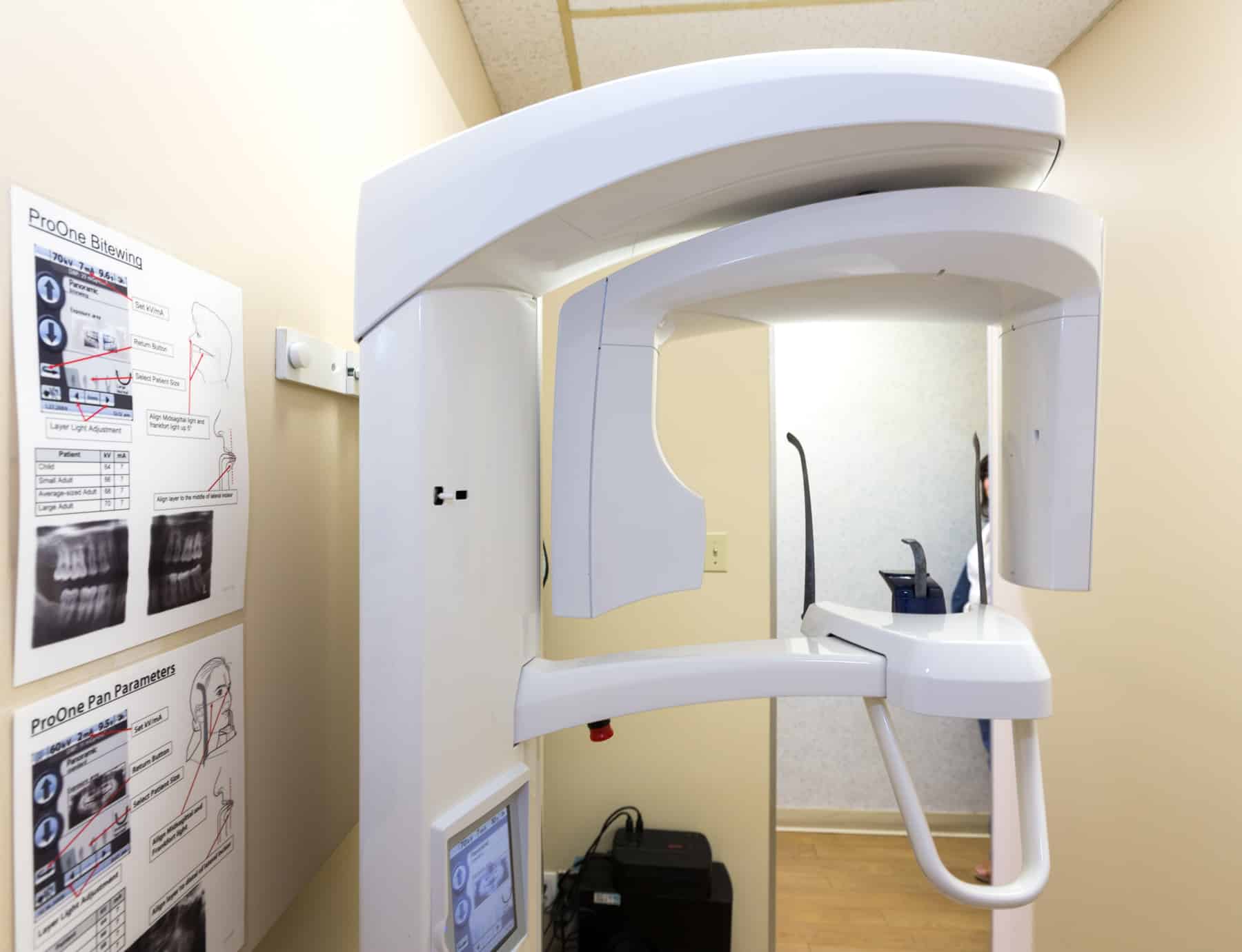 Large piece of dental technology from floor to ceiling used for advanced dental x rays sitting in a dental office with papers on the wall