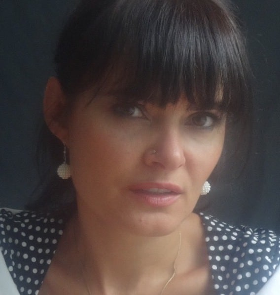 Picture of woman in polka dot dress and white earings with dark solid background