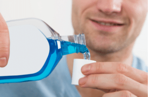 mid adult man pouring bottle of mouthwash into cap